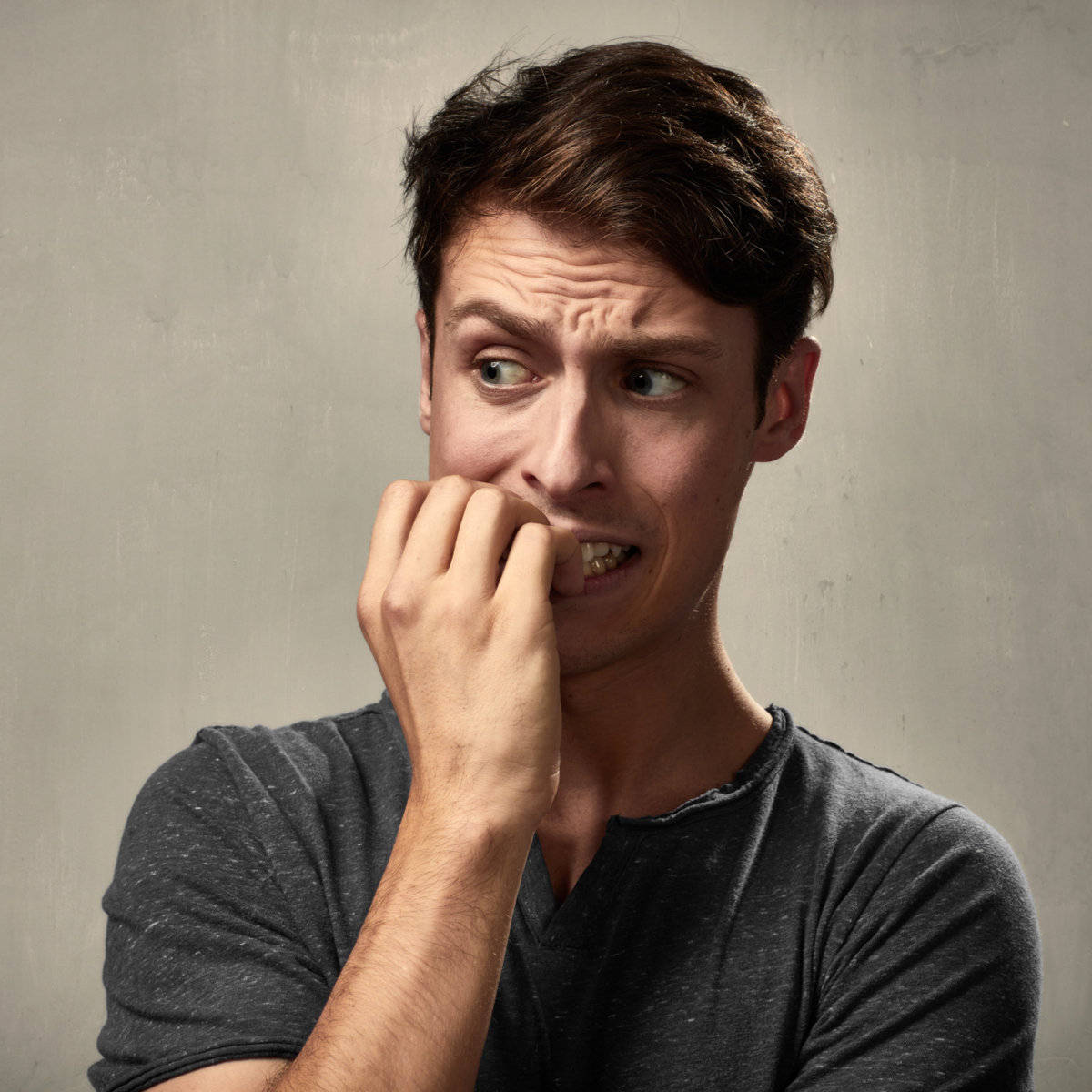 A young man holding his hand in front of his mouth with uncertainty.