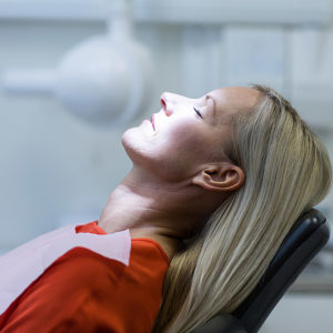 A blonde woman relaxed in a dental chair preparing for treatment.