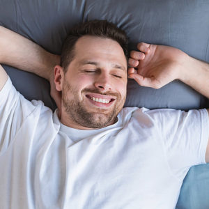 Man smiling in his sleep after being treated for sleep apnea with Vivos