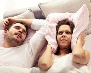 Couple in bed with angry woman mad at snoring husband