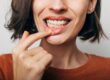Close up shot of gum inflammation. Cropped shot of a young woman showing red bleeding gums isolated on a gray background.