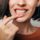 Close up shot of gum inflammation. Cropped shot of a young woman showing red bleeding gums isolated on a gray background.