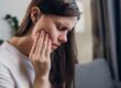 closeup of a woman suffering from jaw pain, hand on side of face