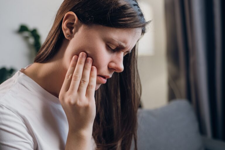 Close,Up,Of,Upset,Young,Female,20s,Touching,Mouth,With closeup of a woman suffering from jaw pain, hand on side of face