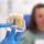 dentist in blue gloves sowing a female patient an implant model