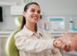 young woman smiling, shaking hands with dental assitant