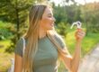 A side view of a woman's smile, outdoors holding Invisalign