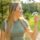 A side view of a woman's smile, outdoors holding Invisalign