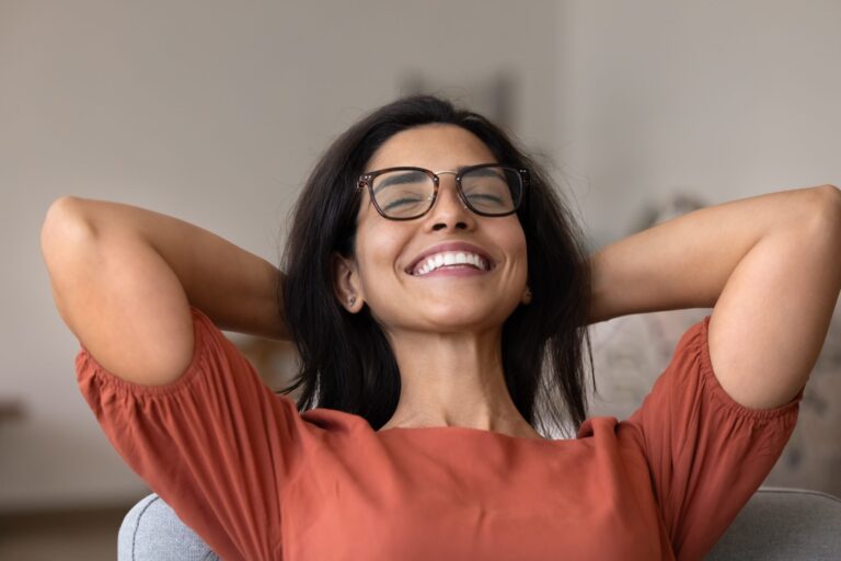 happy young woman with her hands behind her head, smiling, new dental crowns