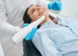 Dentist in uniform using an intraoral camera to examine the inside of the mouth