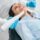 Dentist in uniform using an intraoral camera to examine the inside of the mouth