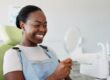 smiling woman in a dental chair looking in mirror, perfect white teeth